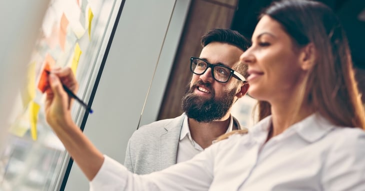 man and woman developing an seo strategy for business on a window with sticky notes