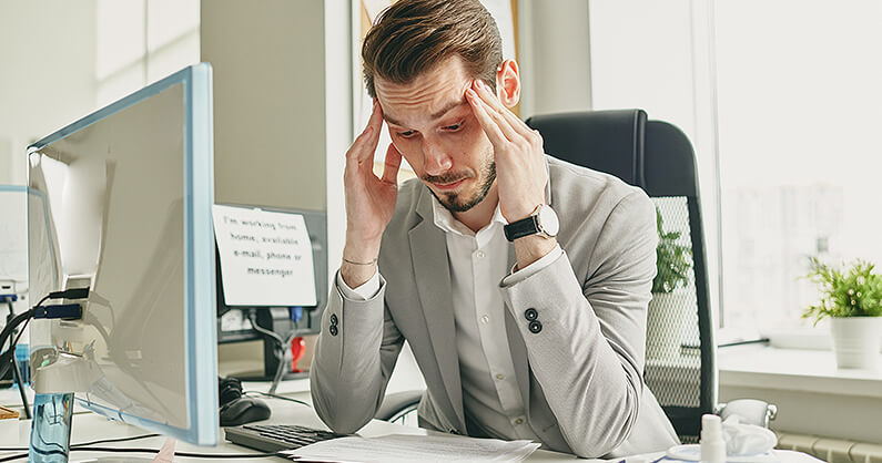 Confused business person sitting at desk behind computer