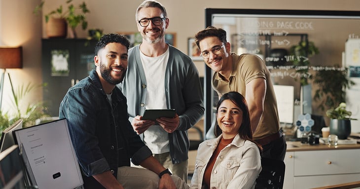 Web design team sitting around computer looking at camera