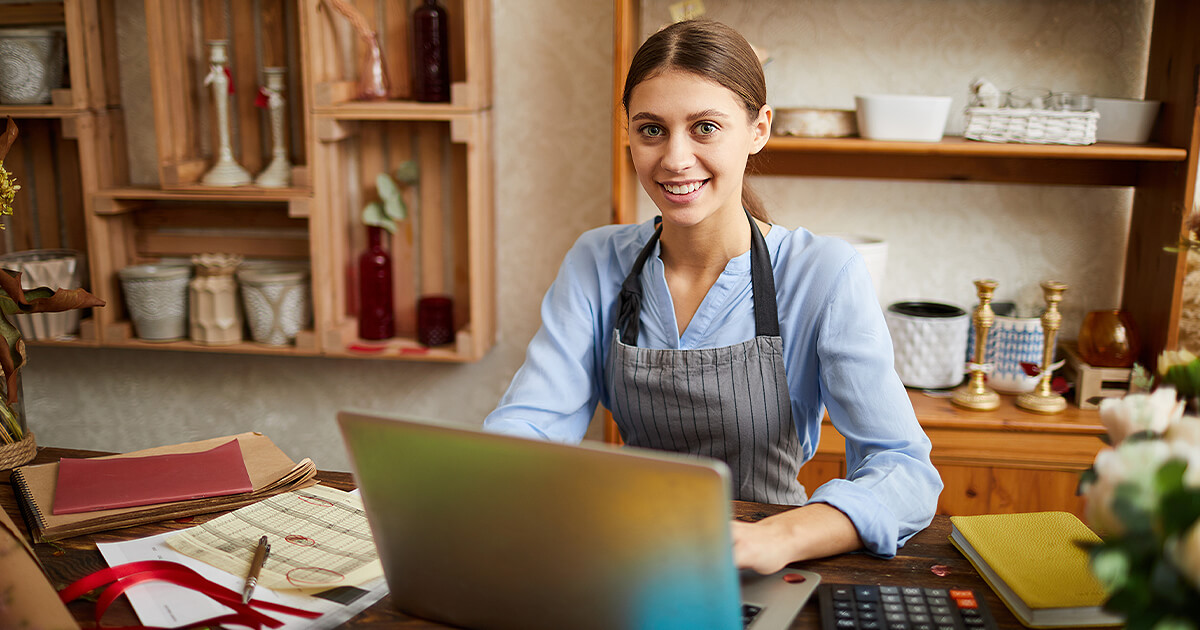 Businesswoman sits at computer at work desk working on business grant application